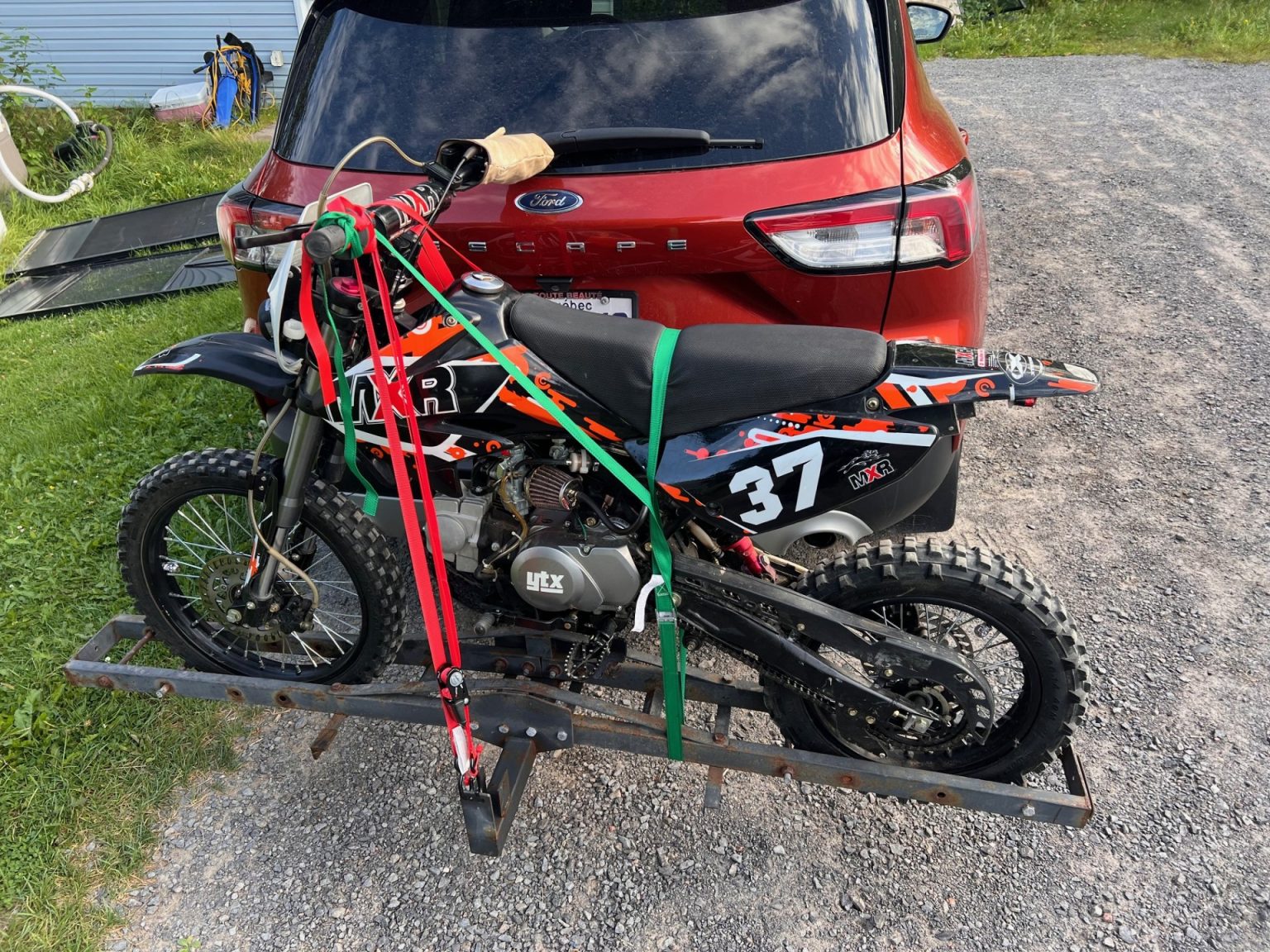 Apollo MXR 125 motocross mounted at the rear of a car, ready for an all-terrain outing.